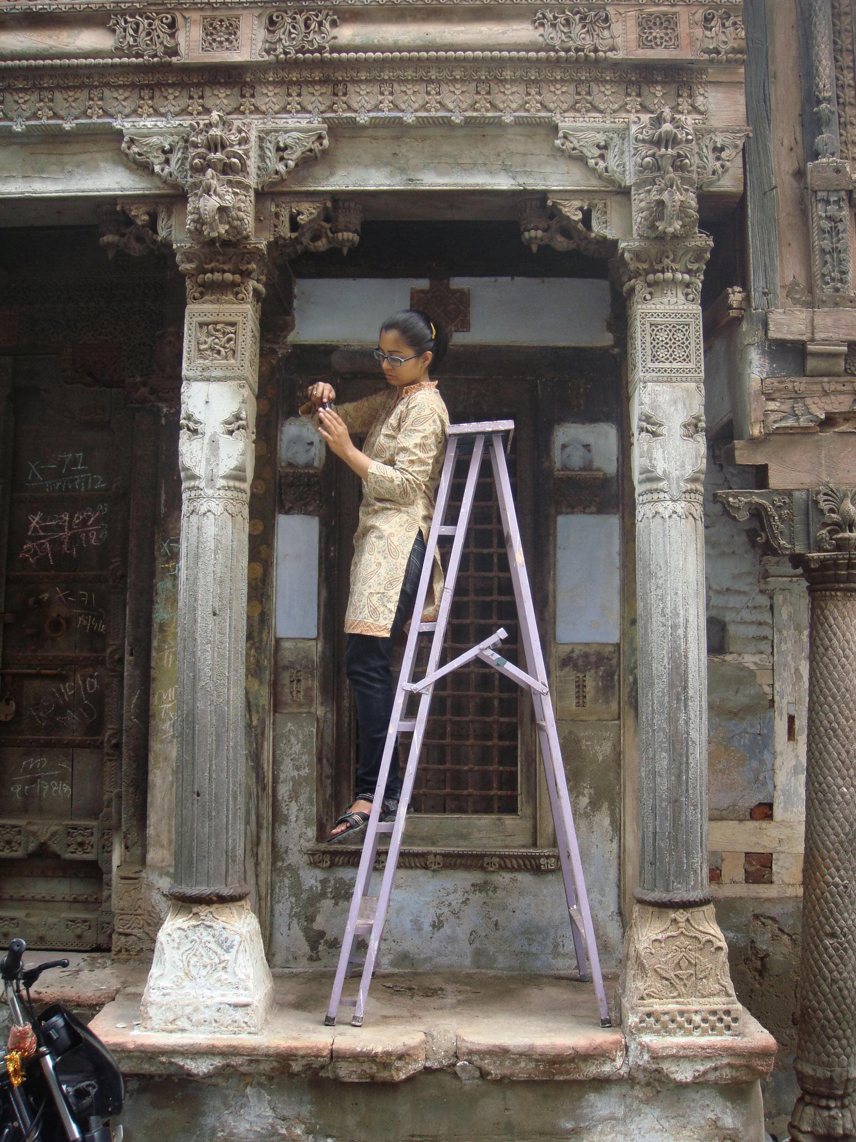 Conservation architect documenting a carved wooden facade during fieldwork